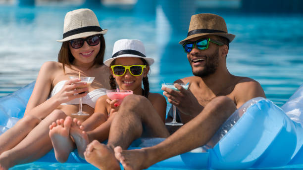 счастливая семья питьевой коктейль в бассейне - fun mother sunglasses family стоковые фото и изображения