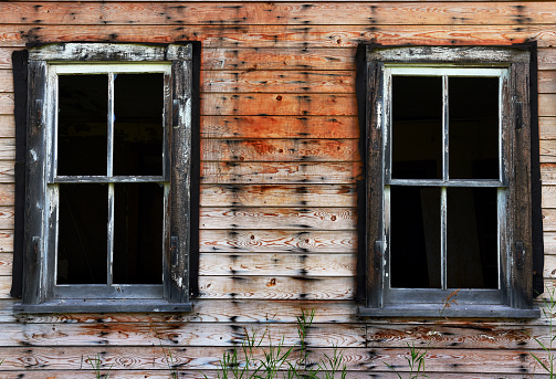 An abstract image of two broken windows on an old abandoned house.
