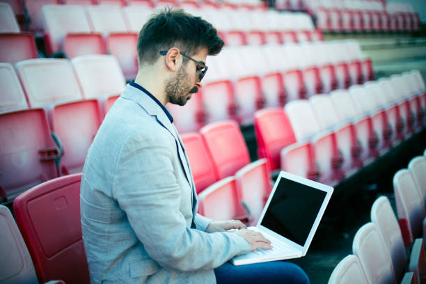 istock Modern footbal coach sitting on tribune and using laptop 836030346