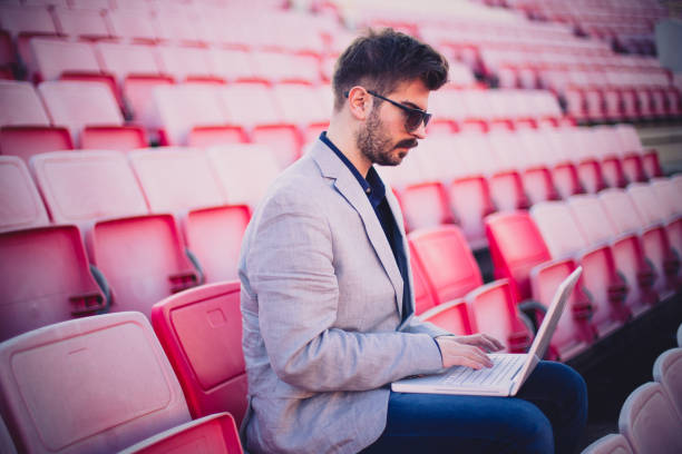 istock Young businessman watching game and using laptop 836030590