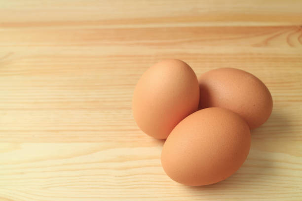 istock Three fresh uncooked hen eggs isolated on the wooden table, with free space for text and design 836030846