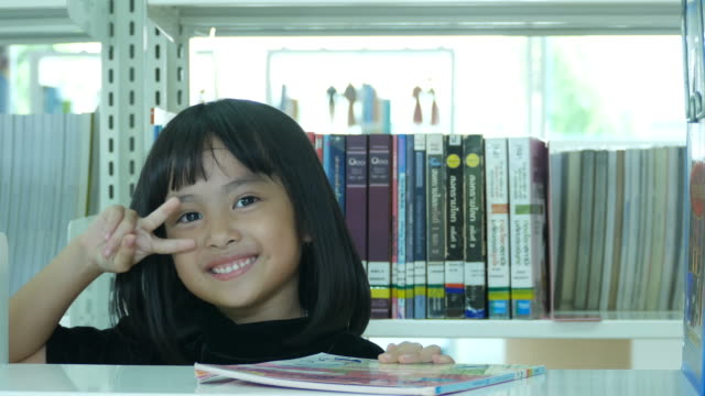 Victory Sign by Asian girl in library