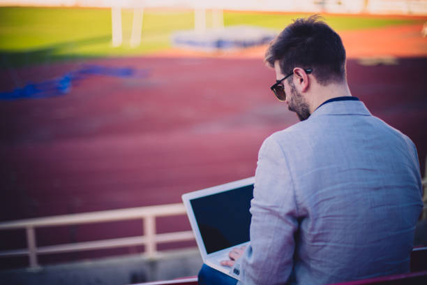 jeune homme d’affaires, regarder match et à l’aide d’ordinateur portable - bureau de pmu photos et images de collection