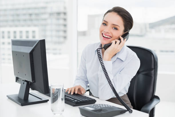 istock Smiling businesswoman using landline phone and computer in office 836070216