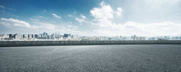 empty road and cityscape of modern city against cloud sky stock photo