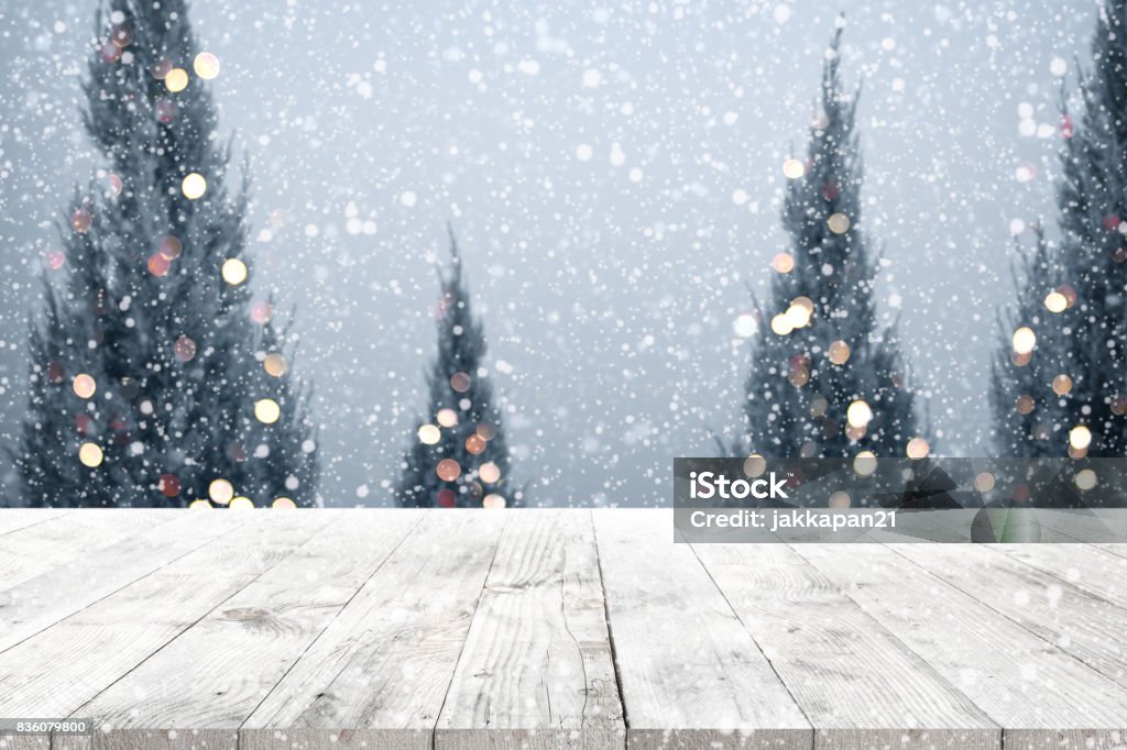 Christmas and New year background Christmas and New year background with wooden deck table over christmas tree, snow and blurred light bokeh. Empty display for product montage. Rustic vintage Xmas background. Backgrounds Stock Photo