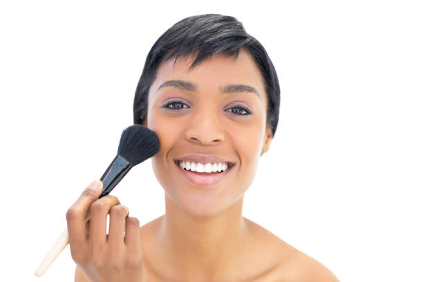 istock Delighted black haired woman applying powder on her cheeks 836083214