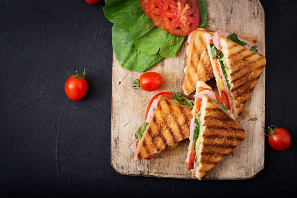 Club sandwich panini with ham, tomato, cheese and basil. Flat lay. Top view Club sandwich panini with ham, tomato, cheese and basil. Flat lay. Top view panino stock pictures, royalty-free photos & images