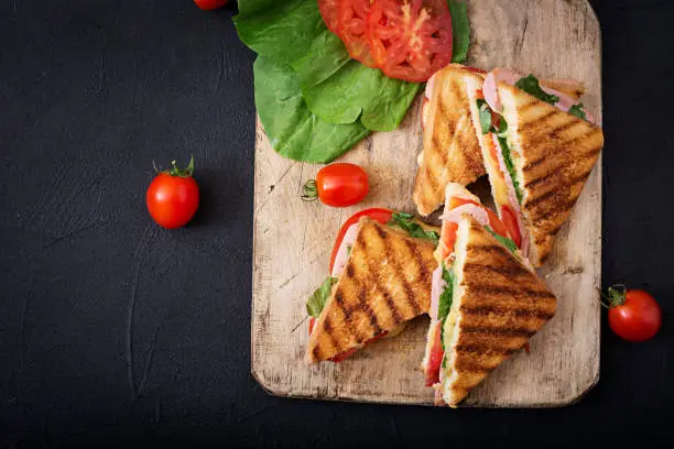 Club sandwich panini with ham, tomato, cheese and basil. Flat lay. Top view