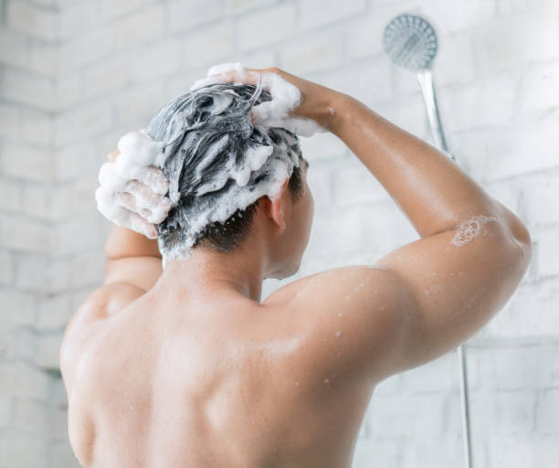 アジア人の男性が浴室でシャワーを浴びて、彼は幸せでリラックスしています。 - shampoo ストックフォトと画像