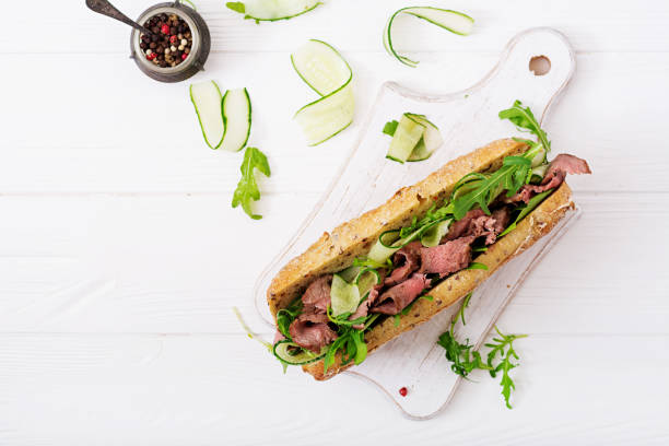 panino di pane integrale con roast beef, cetriolo e rucola. vista dall'alto. laici piatti - green steak food gourmet foto e immagini stock