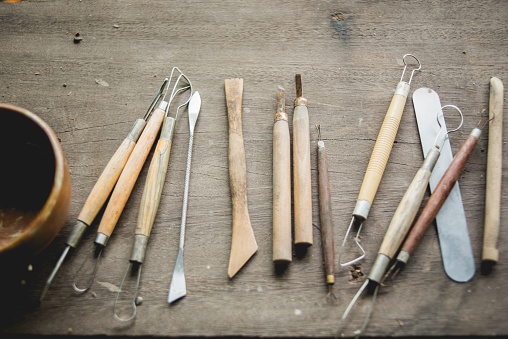 Set of dirty craft sculpting tools on wooden table