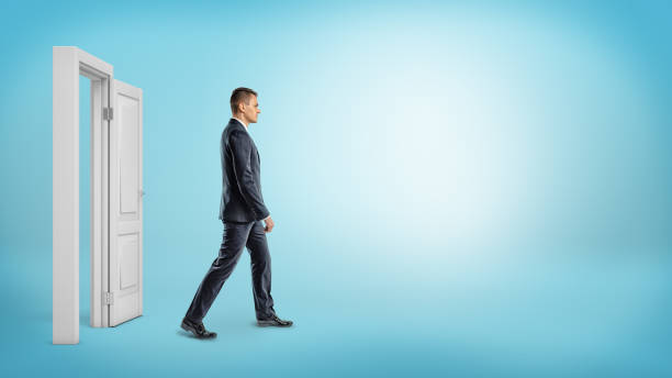 a businessman on blue background walking through an open white doorframe - out side imagens e fotografias de stock