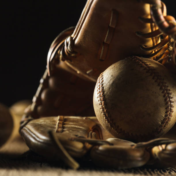 old used baseball Close up image of an old used baseball and baseball glove on wooden table in black background old baseball stock pictures, royalty-free photos & images