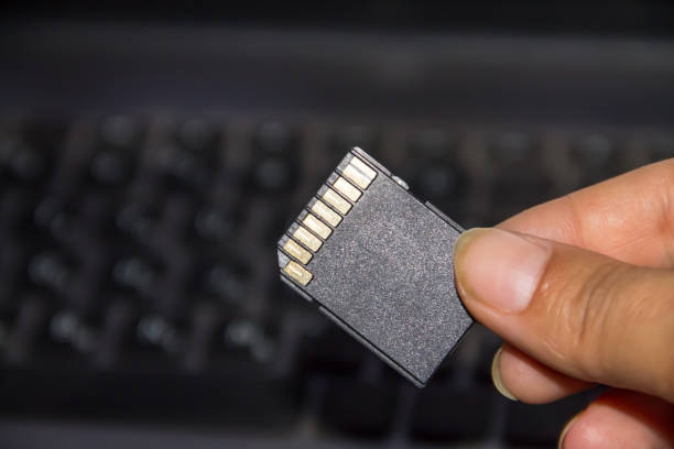 istock Hand holding SD card on laptop background 836142746