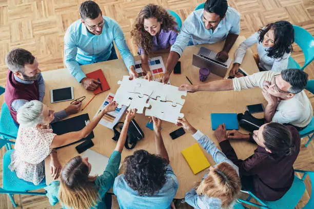 Large group of people holding parts of jigsaw puzzle