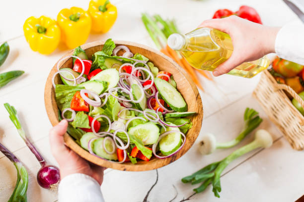 istock man pouring olive oil into healthy salad on kitchen 836151604