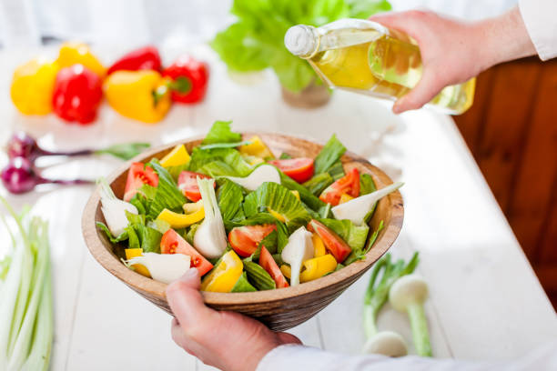istock man pouring olive oil into healthy salad on kitchen 836154566