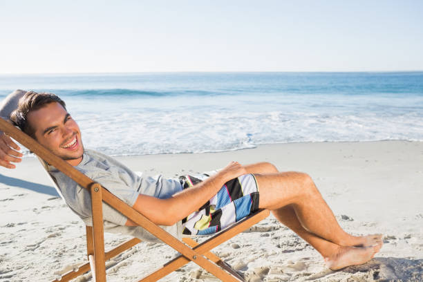 istock Handsome man lying on his deck chair smiling at camera 836154758