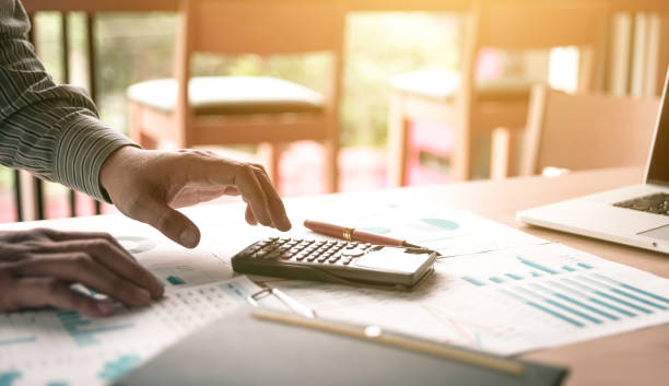 istock Businessman standing and using calculator about summary report on desk in office room. 836154868