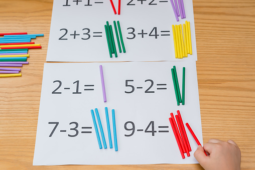 kid learning simple subtraction and addition by counting numbers of sticks