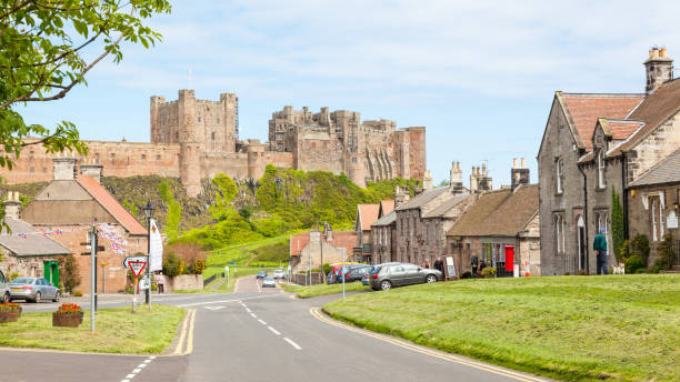 Bamburgh Village and Castle Bamburgh, United Kingdom - June 12, 2012: A view of the picturesque village of Bamburgh, in Northumberland in England, with Bamburgh Castle in the background. Bamburgh stock pictures, royalty-free photos & images