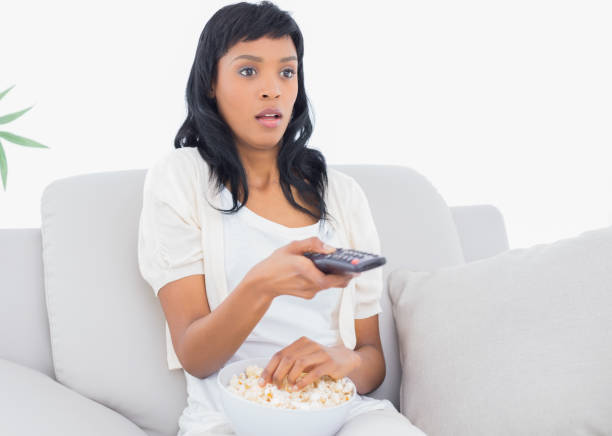 istock Shocked black haired woman in white clothes watching tv while eating popcorn 836167030