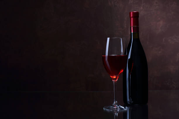 istock Wineglass and bottle with red wine on brown background 836169360