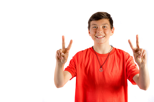 Young teenage boy isolated on white giving double peace sign