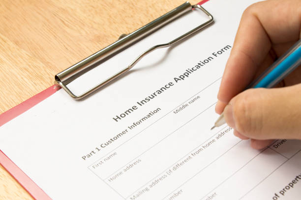 istock Mand fill the home insurance application form with red file on wooden table 836184722