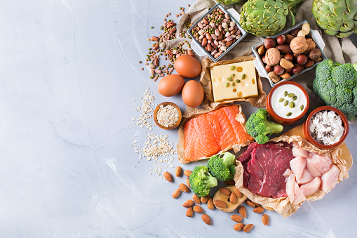 Assortment of healthy protein source and body building food. Meat beef salmon chicken breast eggs dairy products cheese yogurt beans artichokes broccoli nuts oat meal. Copy space background, top view