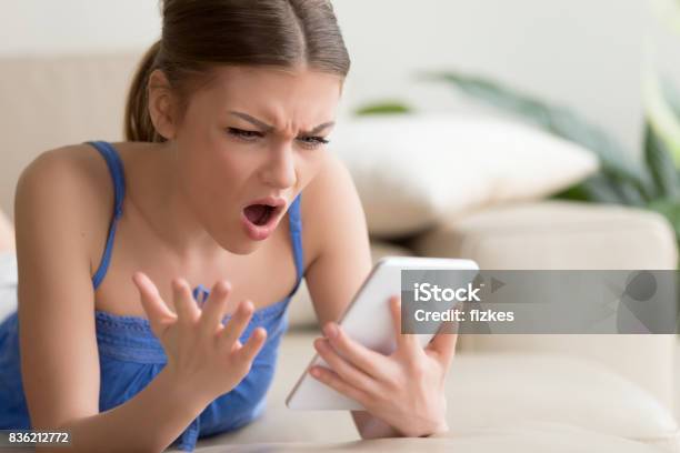 Shocked Young Woman Using Digital Tablet At Home Stock Photo - Download Image Now - Disgust, Women, One Woman Only