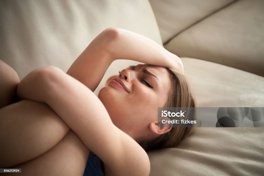 Stressed lady lying on couch at home and crying Stressed young lady lying on couch at home and crying. Unhappy woman suffering from nervous tension, emotional disorders, psychological problems, breakup. Frustrated female feeling lonely and offended Sadness Stock Photo