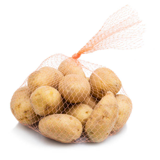 patatas crudas en una bolsa de red aislado sobre fondo blanco - raw potato red potato red vegetable fotografías e imágenes de stock