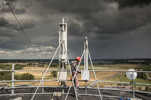 Telecommunication manual high worker engineer installing new 3g 4g LTE antenna on mobile base station (communication tower) located at the top of a water tower. Working at height.