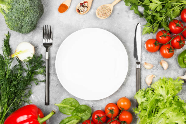 istock Concept dietary and vegetable food. White plate. Various vegetables and spices (broccoli, pepper, cherry tomatoes, garlic, lettuce, parsley, fennel) on a light background. Top view, copy space. Food background 836217300