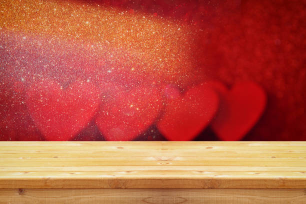 istock Empty wooden table in front of glitter red hearts background 836238388