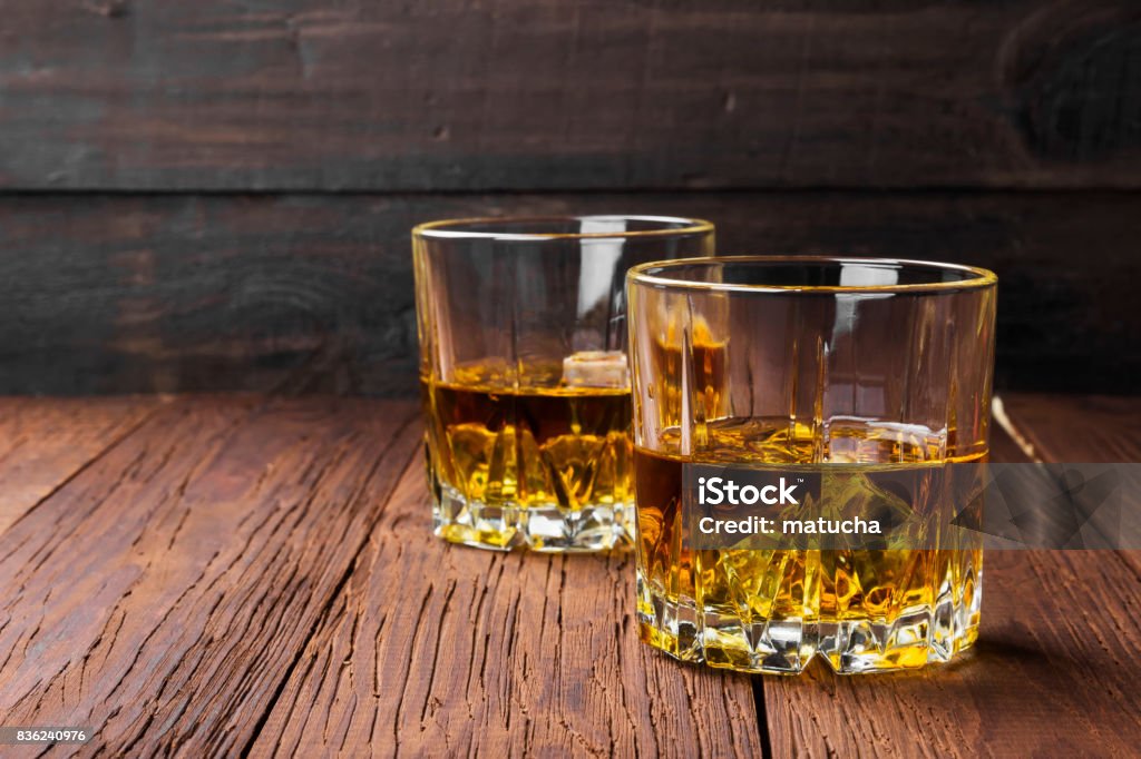 Whisky with ice in two glasses on a wooden background. Copy space. Food background Whiskey Stock Photo