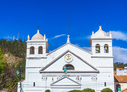 Captured on a radiant sunny afternoon, this image showcases the magnificent exterior of the Inmaculada Concepción Church in Barranquilla, Colombia. The church, a historical and religious landmark, stands proudly under the expansive blue skies. Its gothic-style architecture is highlighted by the ornate facade, intricate stonework, and the presence of stunning stained glass windows that add a colorful vibrancy. The architectural symmetry is evident, with each arch and column meticulously designed, reflecting the church's grandeur and elegance.