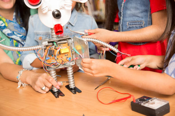 istock Elementary age school girls, teacher build robot in technology class. 836247984