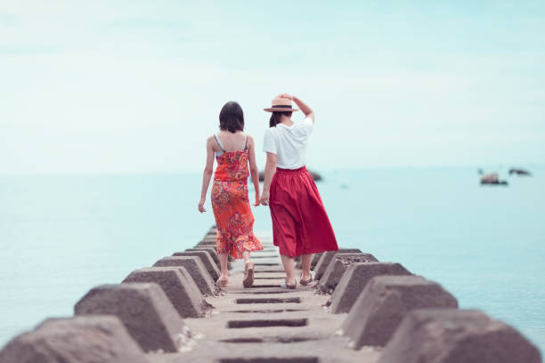 Two Japanese Women Walking To The Sea Two Japanese women are walking to the sea, japanese girlfriends stock pictures, royalty-free photos & images