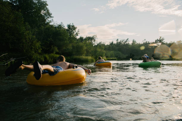 Tubing in river Young people floating down river in inner tubes swimming float stock pictures, royalty-free photos & images