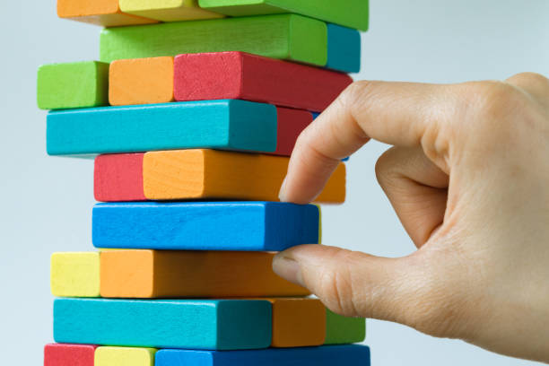 istock Hand pulling colorful wooden block from the tower in as Risk or stability concept 836255128
