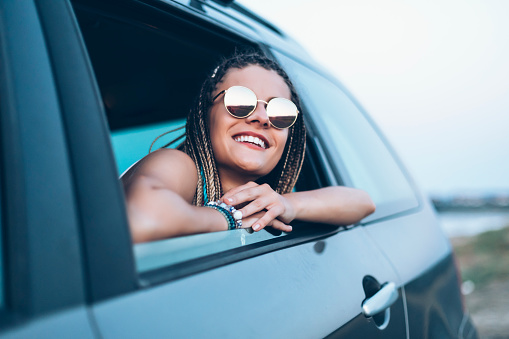 Smiling woman traveling and looking through car window.