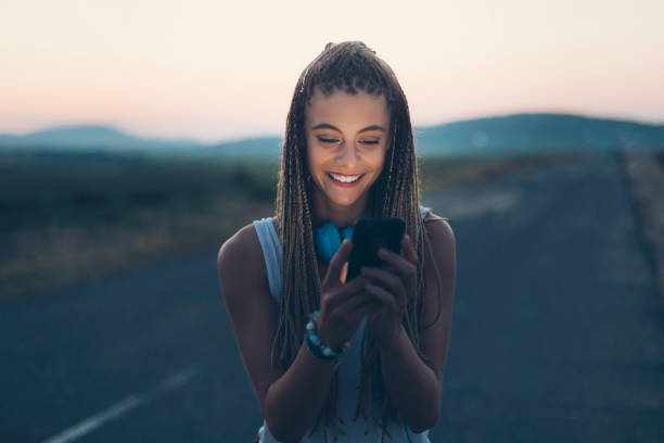 istock Smiling young woman using smart phone on country road 836258082