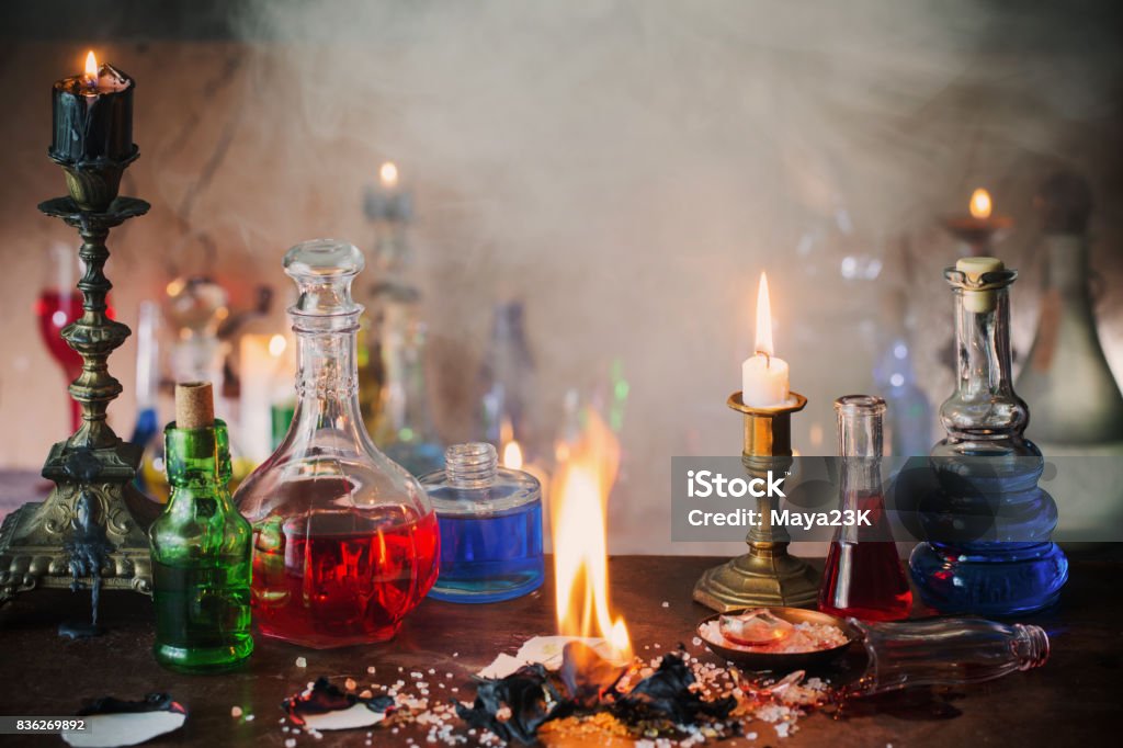 Magic potion, ancient books and candles on dark background Alchemy Stock Photo