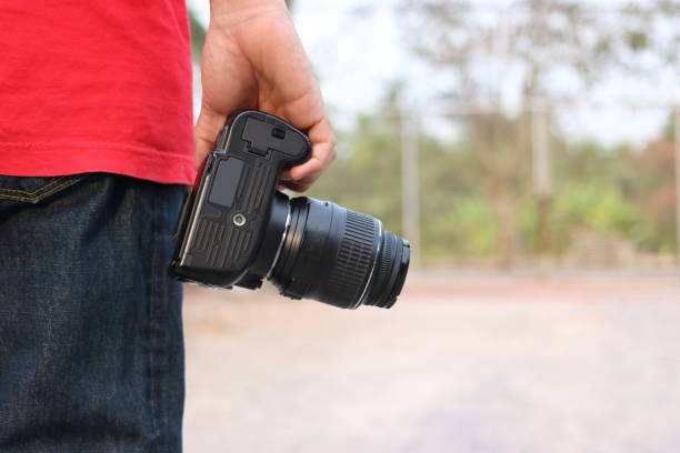 istock Back view of young photographer holding camera on hands with copy space background. 836284262