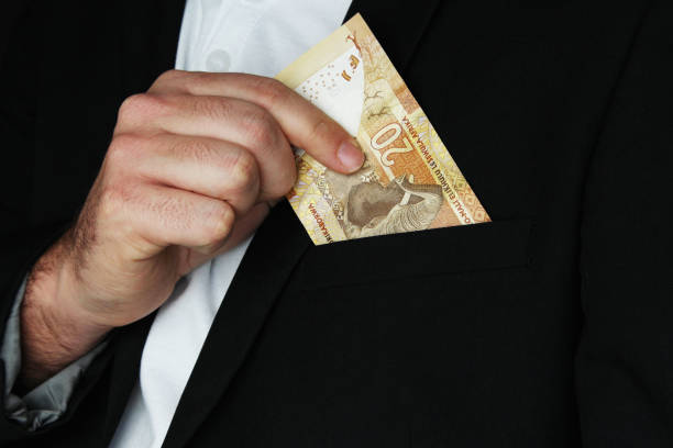 a man putting south african money into his pocket. this image has selective focusing. - ten rand note imagens e fotografias de stock