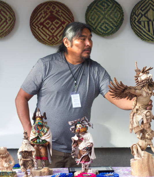 2017 Santa Fe Indian Market: Hopi Sculptor with Kachina Dolls Santa Fe, NM, USA: Hopi artist Arthur Holmes with his carved Kachina dolls at the 2017 Santa Fe Indian Market. The market, now in its 96th year, is spread out around the historic Santa Fe Plaza, showcasing North American Indigenous arts and culture. More than 900 artists from hundreds of tribes participate in the two-day event; visitors number about 100,000. kachina doll photos stock pictures, royalty-free photos & images