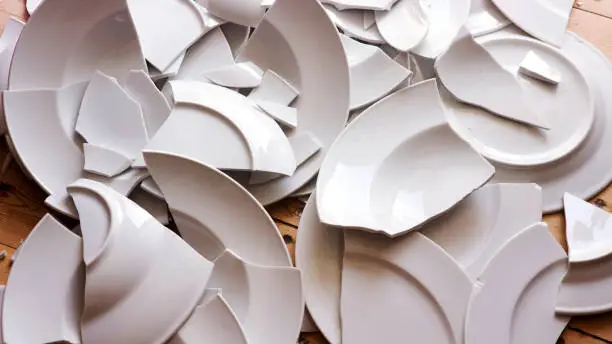 many white broken plates on a wooden floor